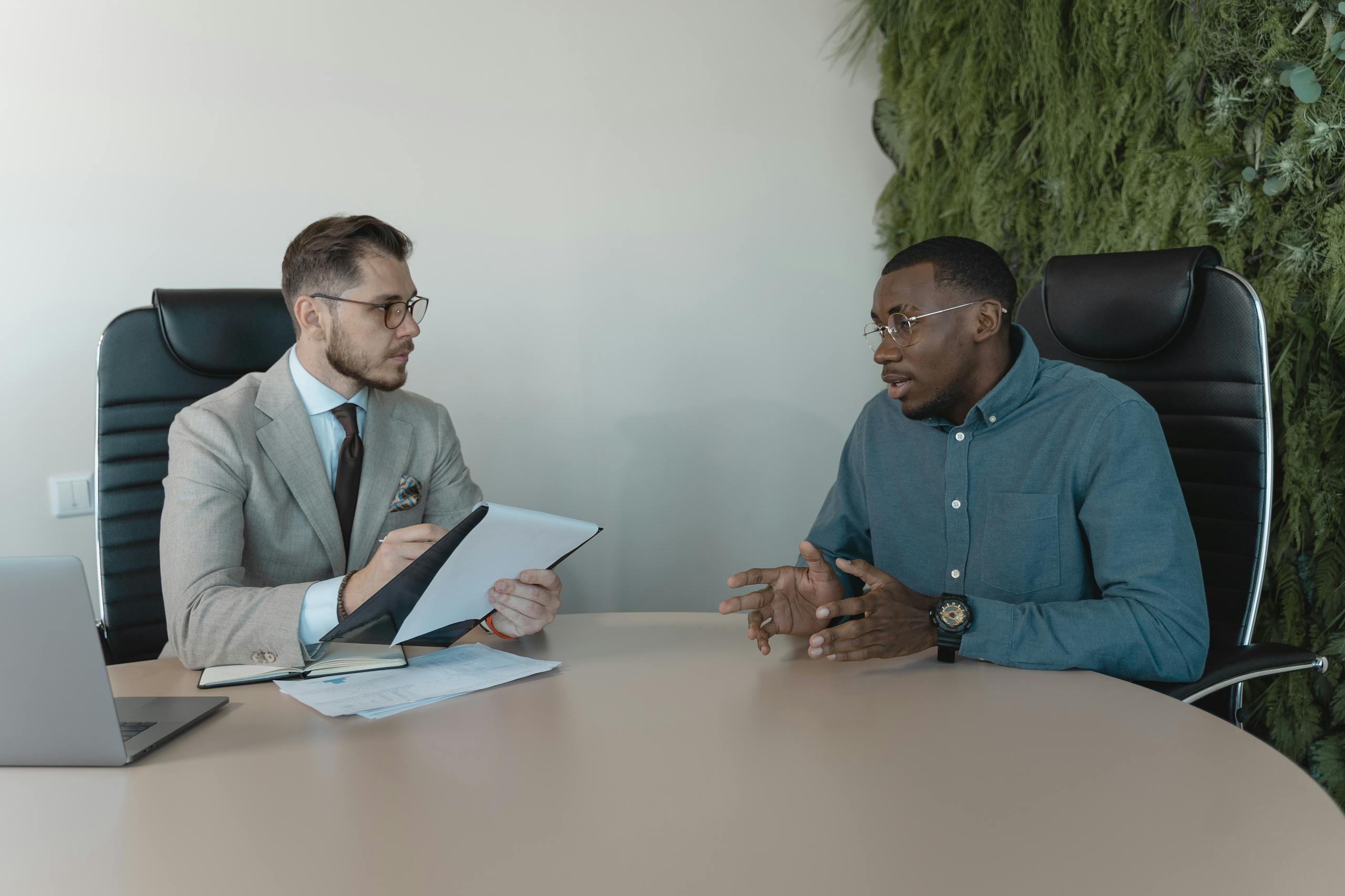 Two businessmen engaged in a discussion during a job interview in a contemporary office environment.